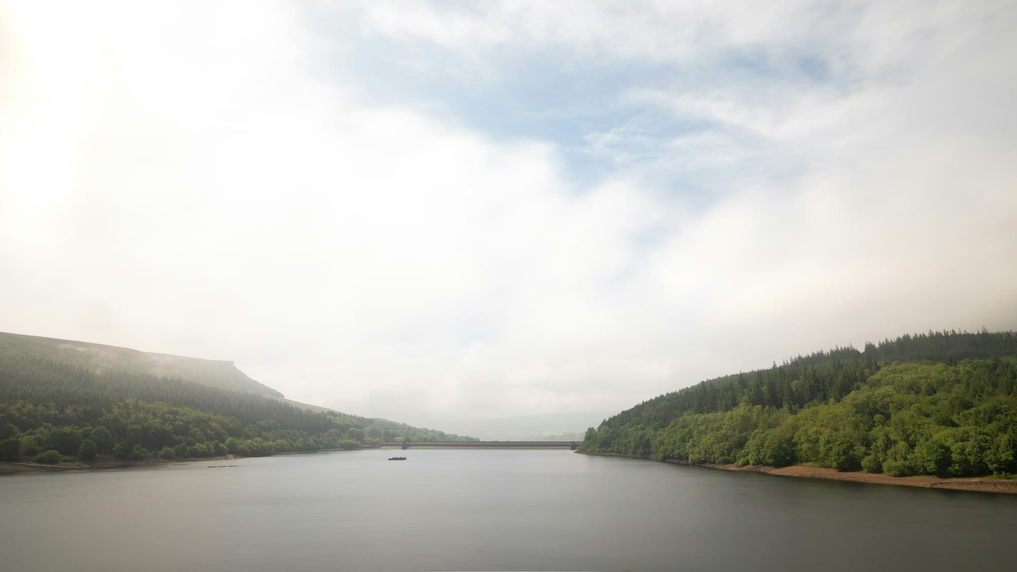 A calm misty lake between forested hills