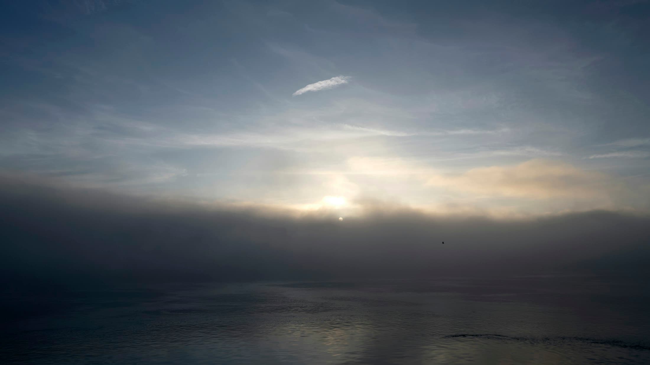 Soft light breaking through fog over calm water