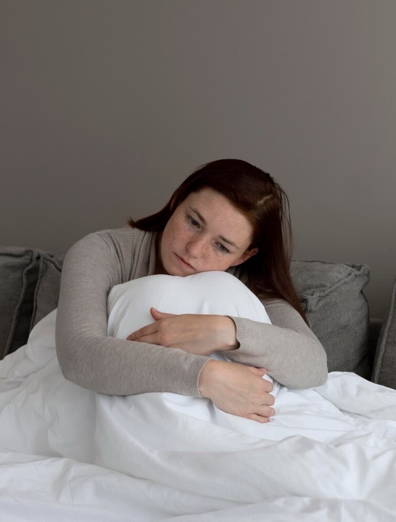 A woman holding a pillow, sitting quietly